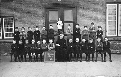 Vught. Broeders van Dongen. St. Aloysius lagere school. Broeder Amantius Simons, een van de oprichters van de school, met leerlingen van de tweede klas. Op de achtergrond het beeld van hun patroon, St. Aloysius, 1929